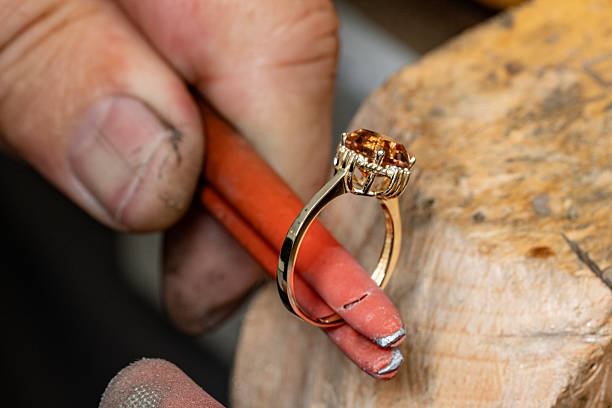 istock Jeweler examines finished gold ring with large orange gemstone 2254637107