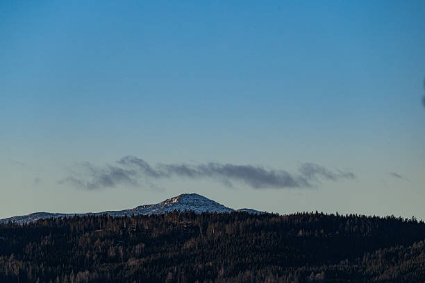 Afternoon winter scene in nature - landscape of mountains covered with snow, fog in the valley and dramatic sky