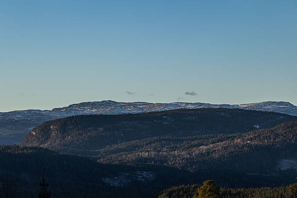Afternoon winter scene in nature - landscape of mountains covered with snow, fog in the valley and dramatic sky