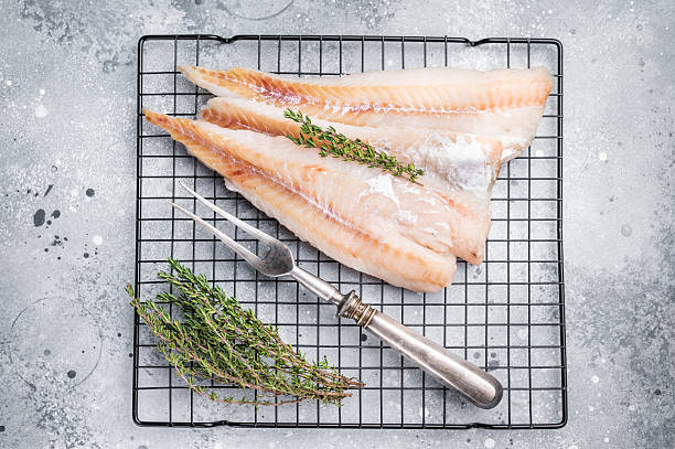 istock Raw pollock white fish fillet with thyme. grey background. top view 2254642108