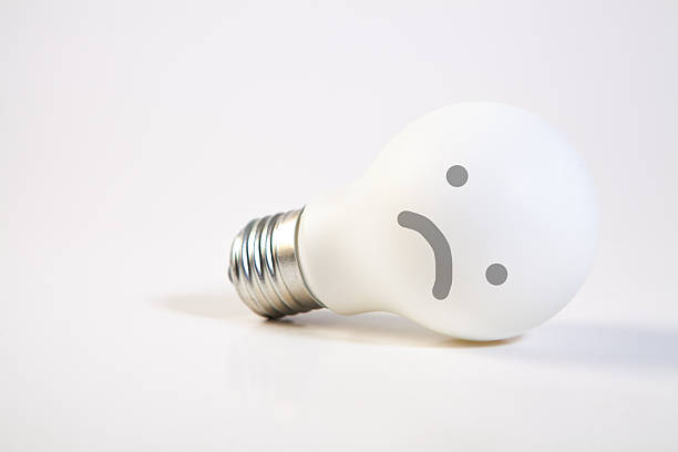 Glowing lightbulb embedded in soil next to a smaller, unlit bulb, representing evolving ideas and sustainable growth