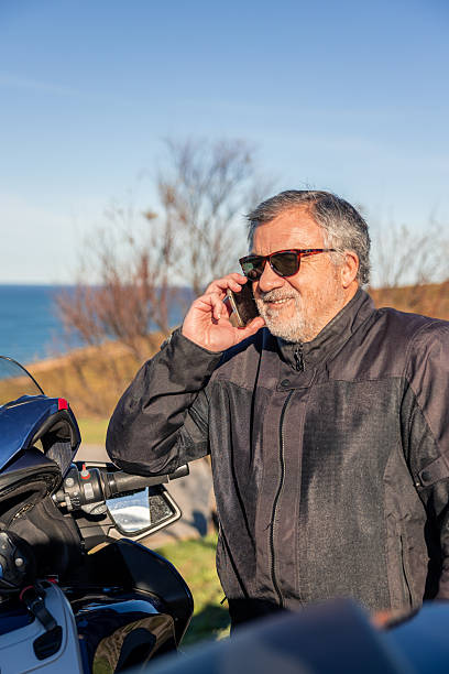 istock vertical Senior man talking on cell phone near motorcycle 2254644237