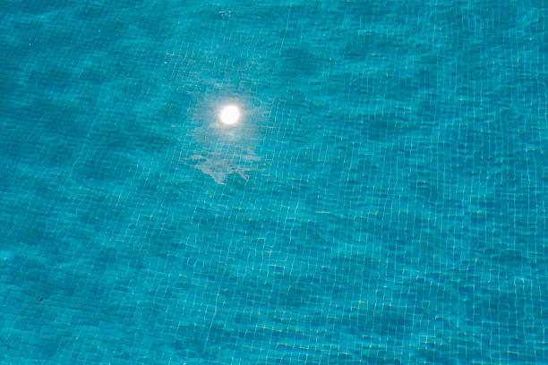 Sunlight reflects and shines on the turquoise pool water. The blue water sparkles and ripples on a beautiful day during a vacation.