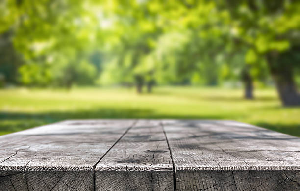 istock Rustic wooden table in sunny park background 2254645591
