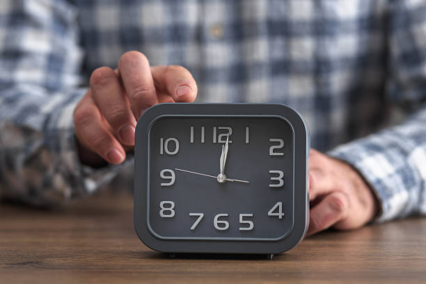 istock Hand stopping alarm clock on office desk 2254645594