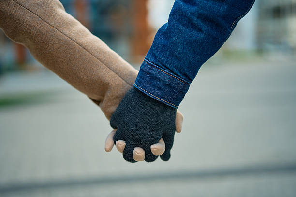 Couple holding gloved hands in winter, walking outdoors in a city and sharing warmth, care and quiet connection that suggests love, support, trust and a shared future