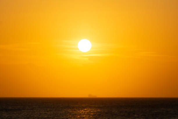 The sun setting over the horizon at sea.