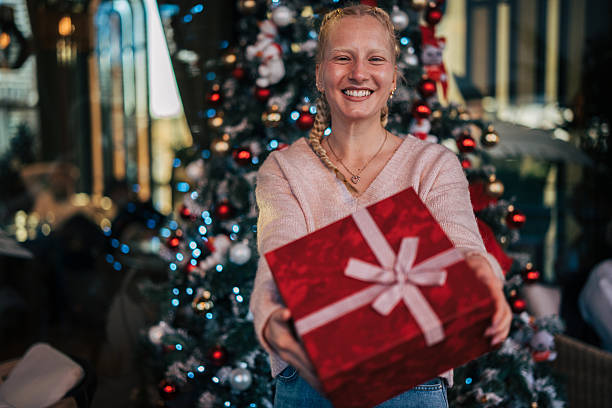 istock Young woman offering christmas gift box smiling 2254656359