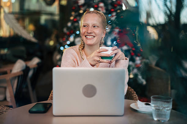 istock Woman drinking coffee and using laptop during christmas holiday 2254656531