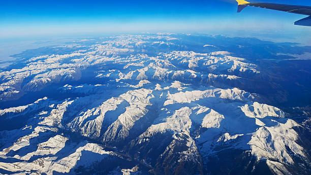 Aerial view shows the snow-covered Pyrenees mountains under a clear sky. The landscape offers a wide perspective, ideal for adding text or exploring the natural scenery.
