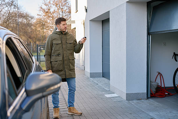 istock Man standing outside house near parked car using remote control to open garage door 2254662413