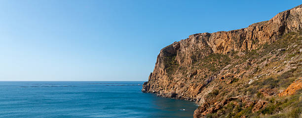 A beautiful blue ocean with a rocky cliff in the background. The ocean is calm and peaceful, and the cliff adds a sense of grandeur to the scene