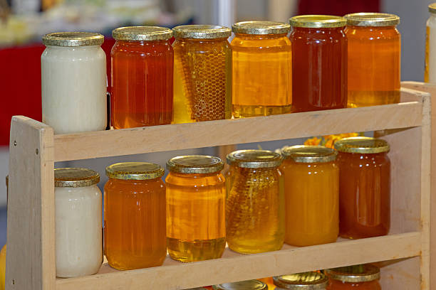 Glass Jars of Natural Sweet Bee Honey With Honeycomb at Wooden Shelf