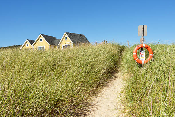 Sandy beach access over marram garss and safety lifebuoy on a sunny summer day