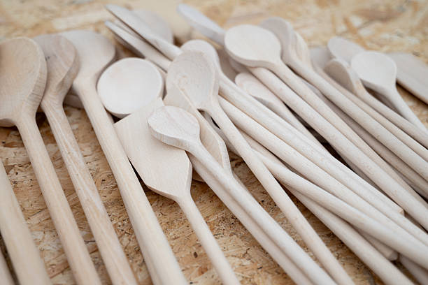 Satisfied cat - a cook with a wooden spoon in his paw on a white background.
