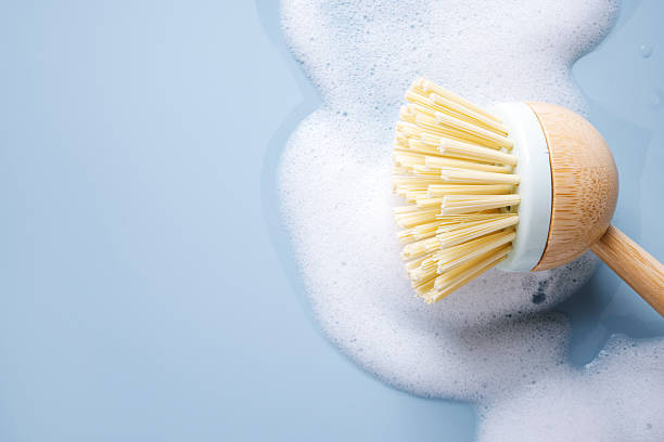 istock Sustainable bamboo dish brush cleaning with white soap suds on blue surface 2254671270