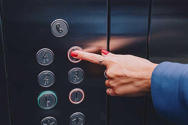 istock Business user hand with red nails pressing illuminated button for desired floor inside modern lift cabin 2254671419