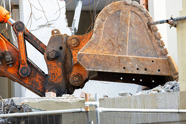 Excavator stands on rubble of house. Dismantling process, demolition of old building, destruction of dilapidated housing