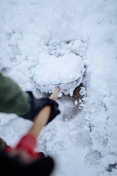 istock Person using a shovel to clear snow from a sidewalk during winter 2254673178