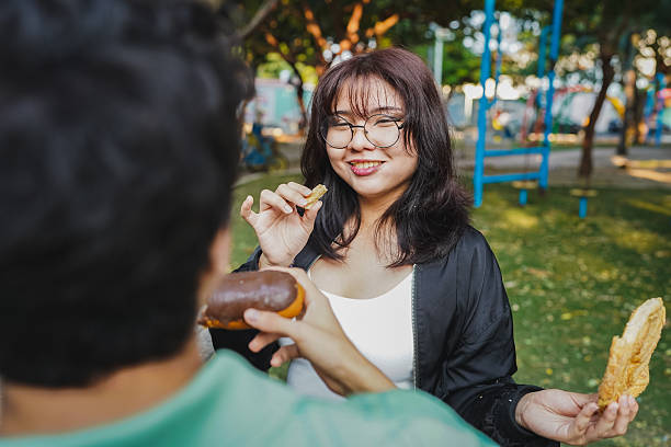 Happy young couple enjoying a snack and conversation together in a sunlit park