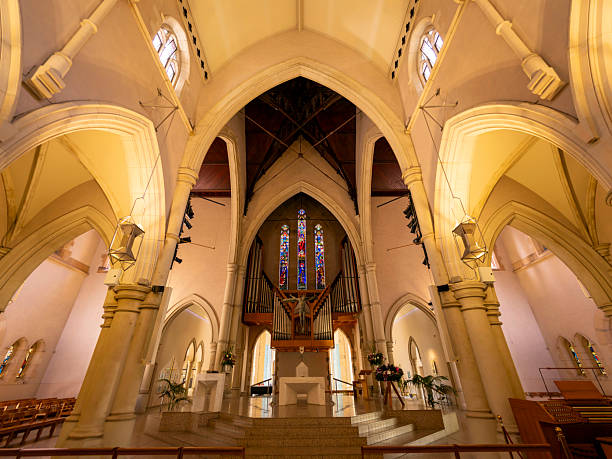 The nave of the cathedral showing Gothic Revival architectural style and a suspended Resurrection Crucifix above the altar.