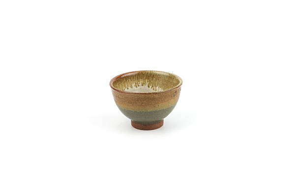 istock An artisan ceramic bowl with a striking earth tone layered glaze (brown, green, and beige), a rustic texture and natural rim isolated on a white background. Tea ceremonies, and home decor styling. 2254687848