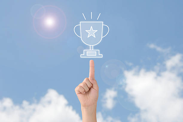 Child's hand pointing at a trophy towards the blue sky