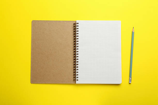 istock Notebook and pencil on yellow background, top view 2254698095