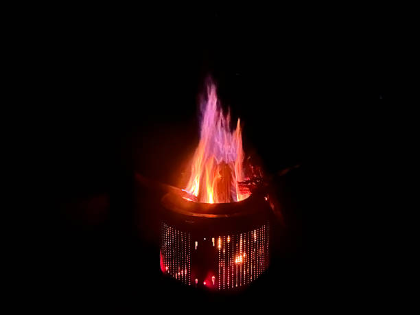 a roaring campfire contained within a fire pit at night, with bright flames illuminating the surrounding darkness in an outdoor setting