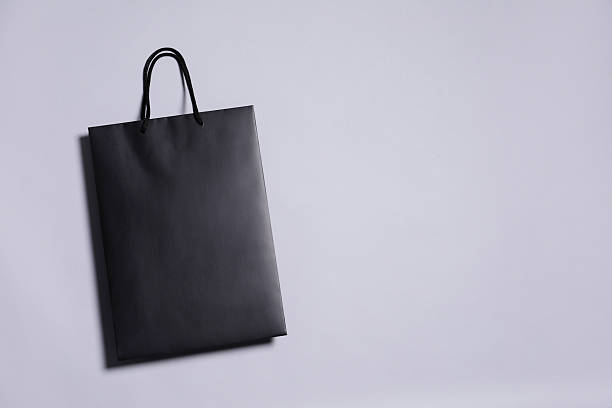 istock One black paper shopping bag on grey background, top view. Space for text 2254707771