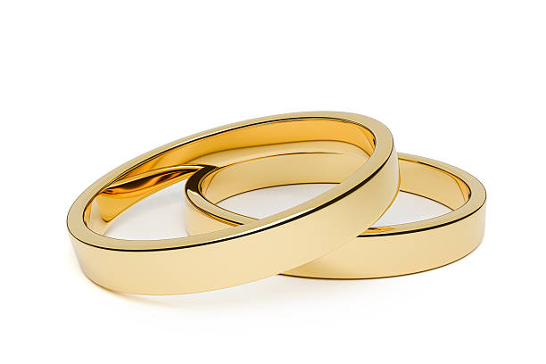 Two shiny gold wedding rings interlocked and isolated on a white background. Symbol of marriage, love, commitment, and lifelong partnership. Elegant and minimal jewelry concept suitable for wedding invitations, jewelry advertising, romantic designs, and relationship-themed projects.
