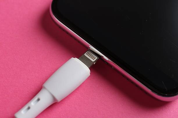 USB charge cable and smartphone on pink background, closeup