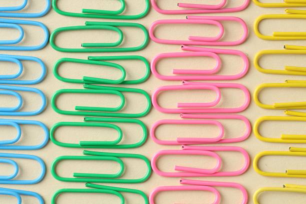 Colorful paper clips on beige background, flat lay