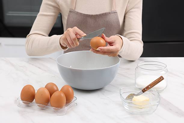 istock Making dough. Woman adding egg into bowl at white marble table, closeup 2254713250