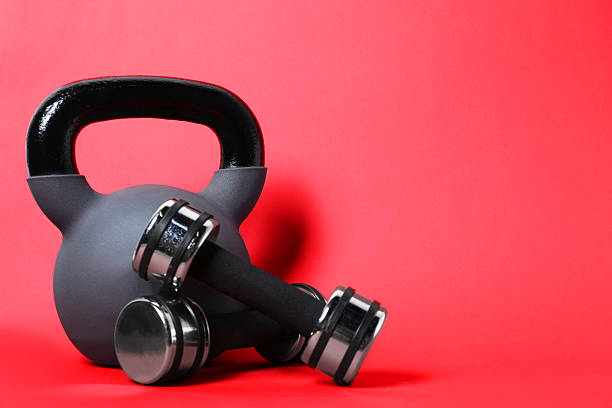 Kettlebell and dumbbells on red background. Space for text