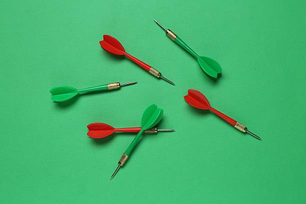 Colorful dart arrows on green background, flat lay