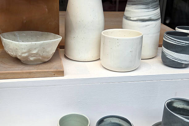 A collection of minimalist ceramic pottery featuring various shapes and sizes, emphasizing neutral tones with speckled finishes. showcased on a white shelf, ideal for modern interior design and home decor inspiration.