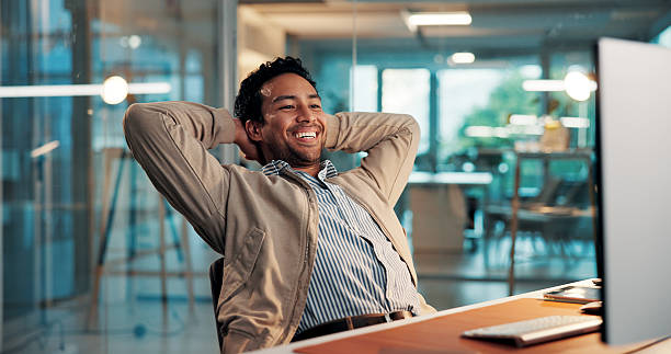 istock Computer, relax and smile with business man at desk in office for complete task or satisfaction. Done, hands behind head and PC with happy employee in workplace for planning, research or stretching 2254719286
