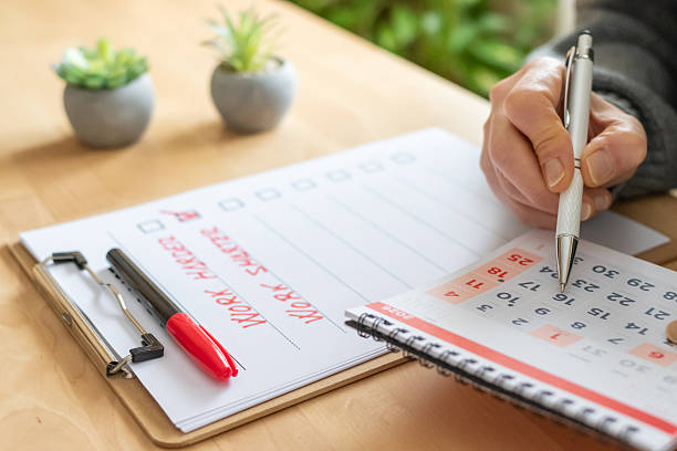 istock Hand holding a pen, marking dates on a calendar and writing work harder and work smarter on a to-do list, emphasizing efficiency and strategic planning 2254720975