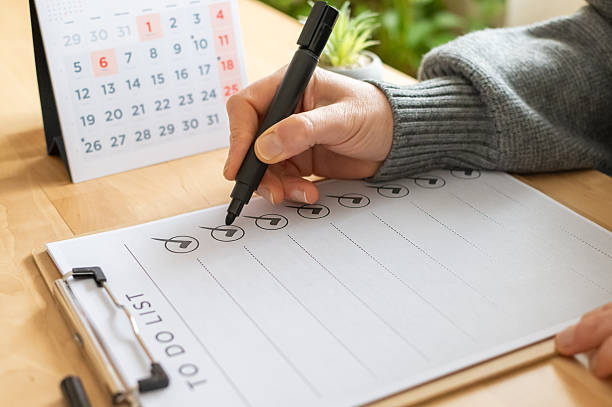 istock Hand using a marker pen, checking off items on a to do list sheet on a clipboard with a desktop calendar in the background, showing planning and organization 2254720977