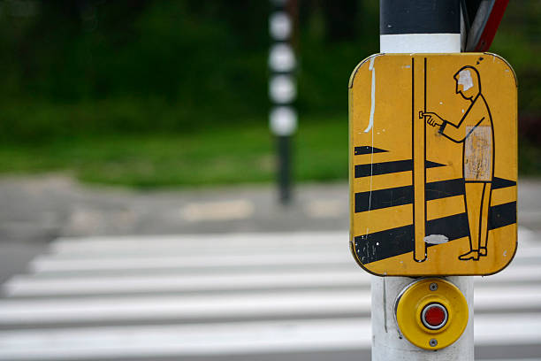Yellow pedestrian crossing warning sign with black stripes and button detail showing urban safety infrastructure