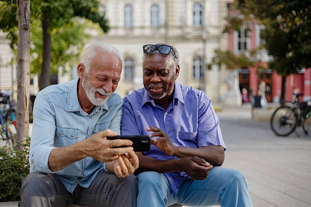 istock Elderly Black and White Men Watching Video on Phone in Public Square – Real Interaction 2254730952