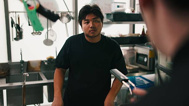 Young asian man working as chef in commercial kitchen. Culinary professional at work