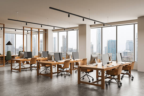 istock Modern open space office interior with wooden desks, rolling chairs, and large windows showing cityscape background with natural daylight atmosphere. 3D Rendering 2254731758