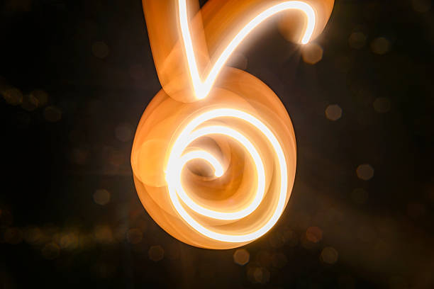 Abstract image featuring flowing light trails, creating curved lines with a warm, glowing tone. The light paints an organic, dynamic texture against a dark background