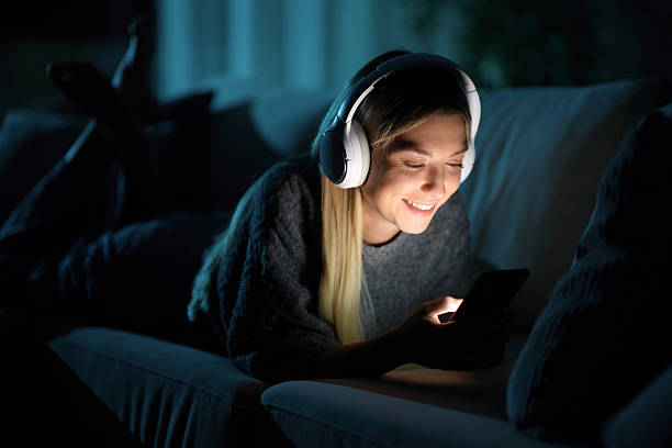 istock Happy woman wearing headphone using phone in the night 2254733113