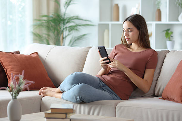istock Serious woman using cellular on a couch at home 2254733130