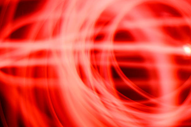 Abstract image of red neon light painting in a circular and spiral pattern against a black background. A modern and futuristic design element