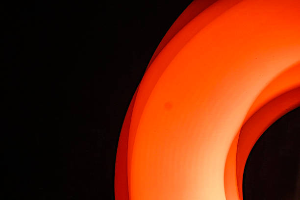 Pleated paper arranged dynamically, highlighted by side lighting in red tones.