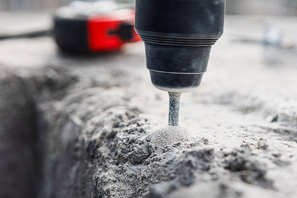 Drill bit boring into dusty concrete surface stock photo